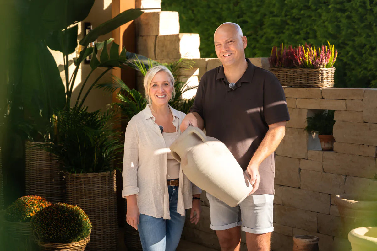 Kasia und Thorsten stehen im Hof und halten eine helle Amphore