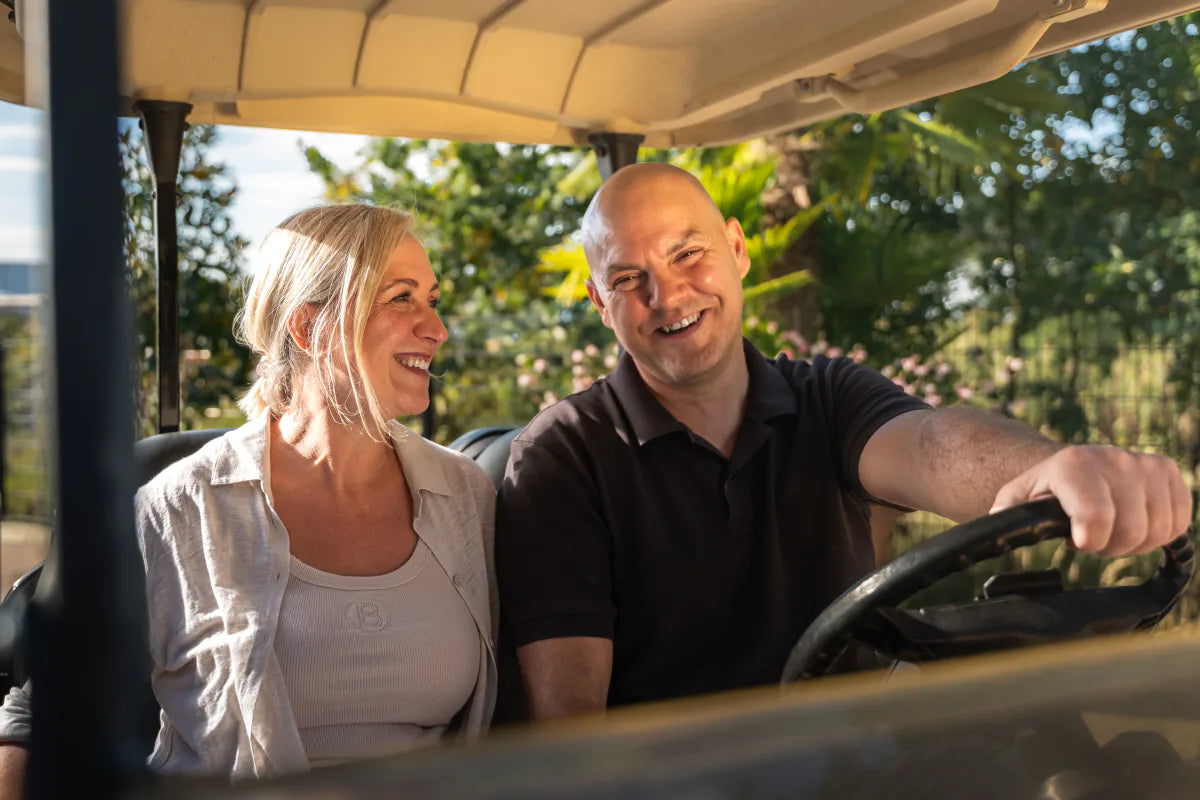 Kasia und Thorsten sitzen lachend in einem Golfcart